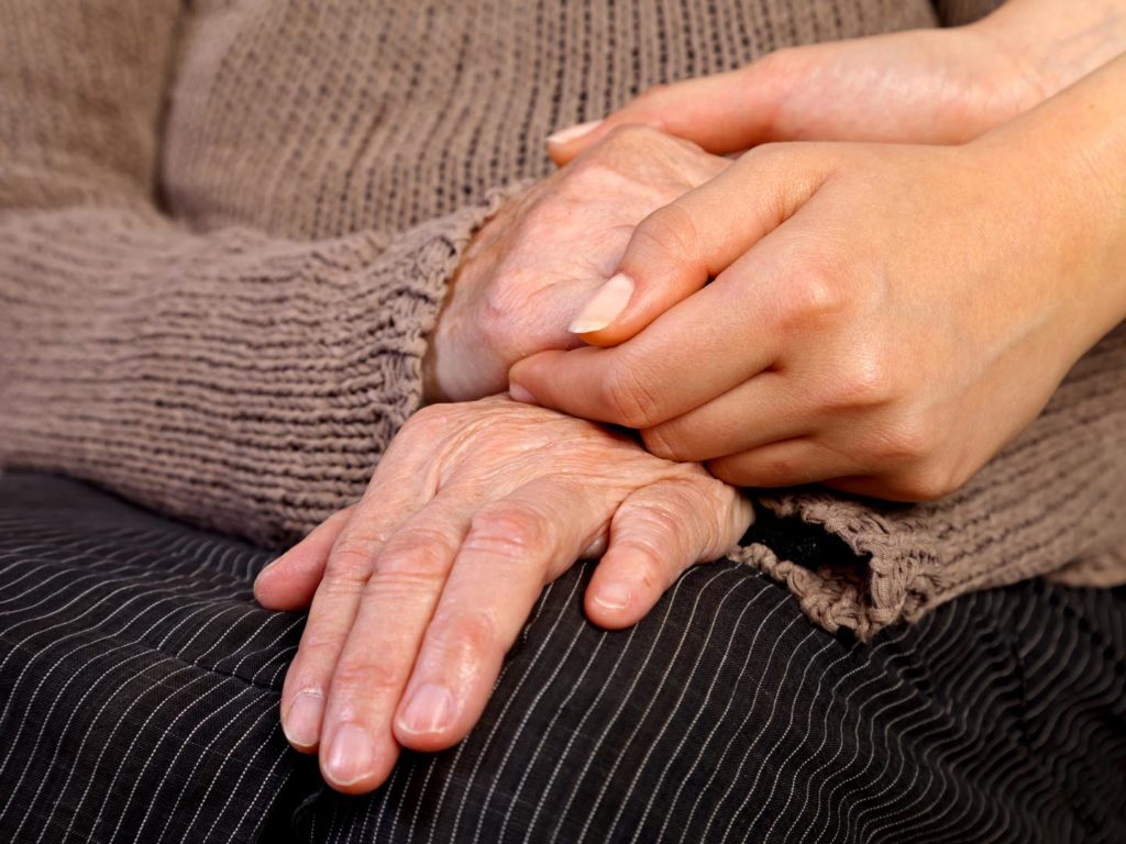Nurse holding elderly wrinkled hand