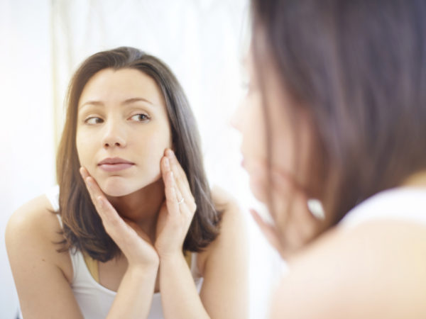 Over the shoulder shot of an attractive young woman looking at her reflection in a mirror