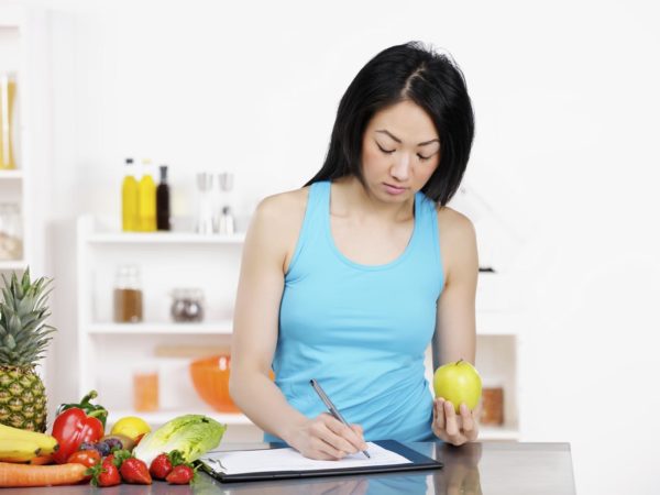 Asian female Nutritionist documenting diet plan.