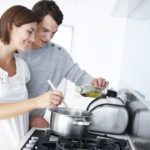 A happy young couple preparing a meal together in the kitchen