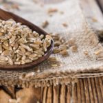 Portion of Spelt on dark wooden background (close-up shot)