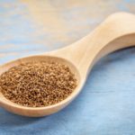 teff grain on a wooden spoon against blue painted grunge wood