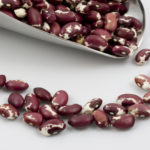 &quot;A scoop of spotted, purple and white Anasazi beans on white background.&quot;