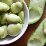 Broad beans fava beans in bowl on wooden table. Summer vegetables, legumes. Top view.