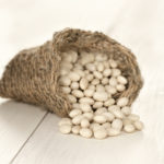 Close up white beans on white wooden table. Macro shoot with selective focus. Shallow DOF