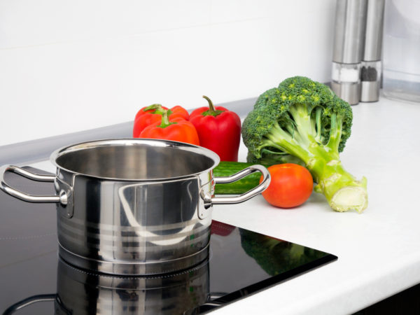 Pot and vegetables in modern kitchen with induction stove