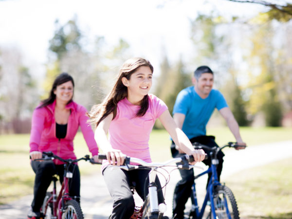 A family riding bicycles together on a bike path in the park on a beautiful sunny day.