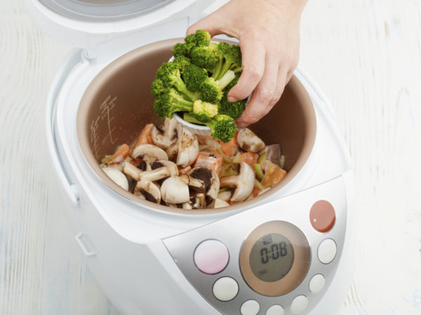 cooking salmon with mushrooms and broccoli in multicooker closeup