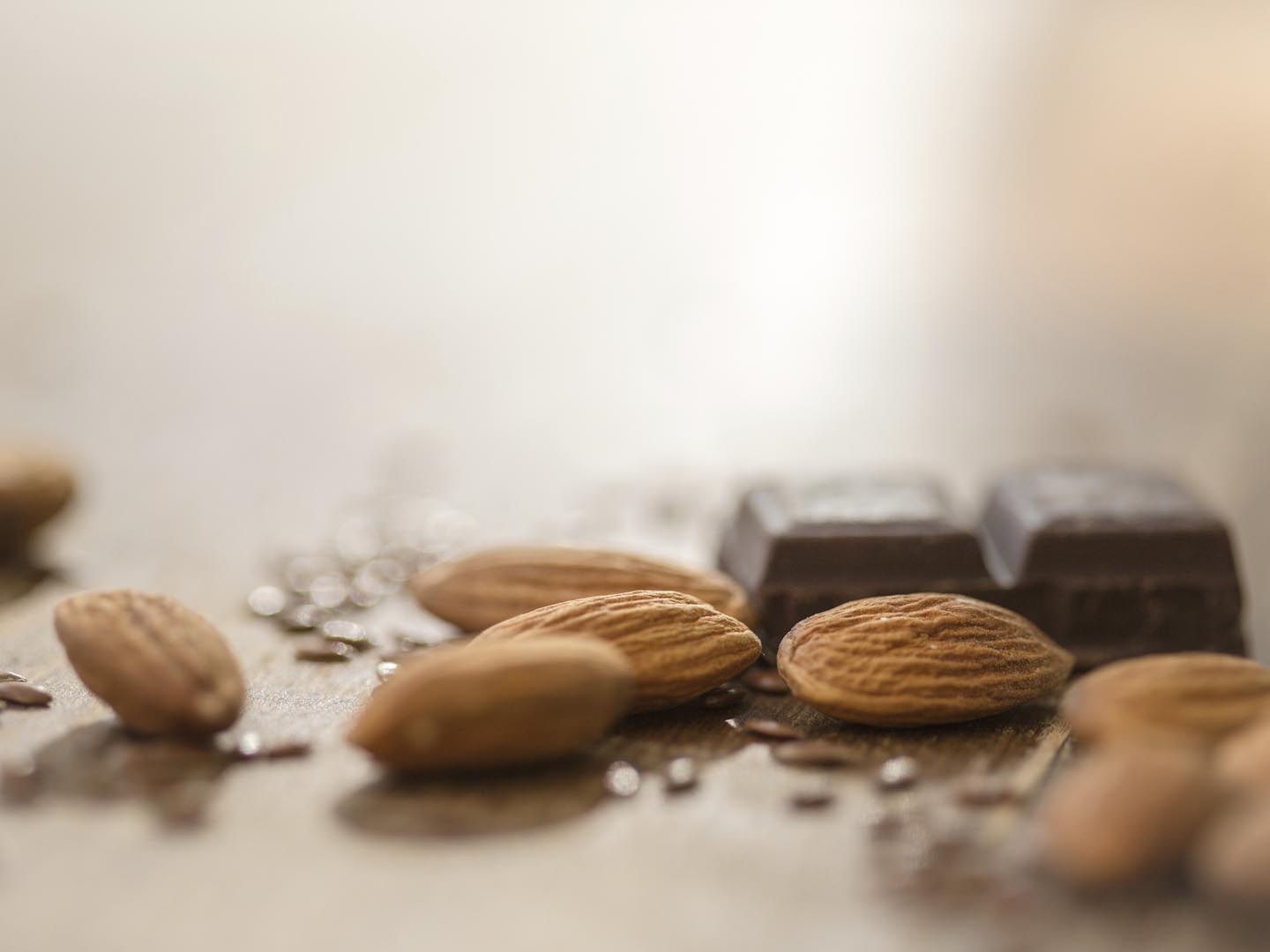 Almonds, flax seed and chocolate on wooden table.