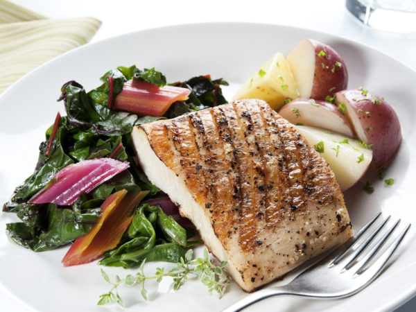 SEVERAL MORE IN THIS SERIES. Grilled portion of mahi-mahi with sauteed rainbow chard and new potatoes. Image could work for other kinds of white-fleshed fish. Shallow DOF.