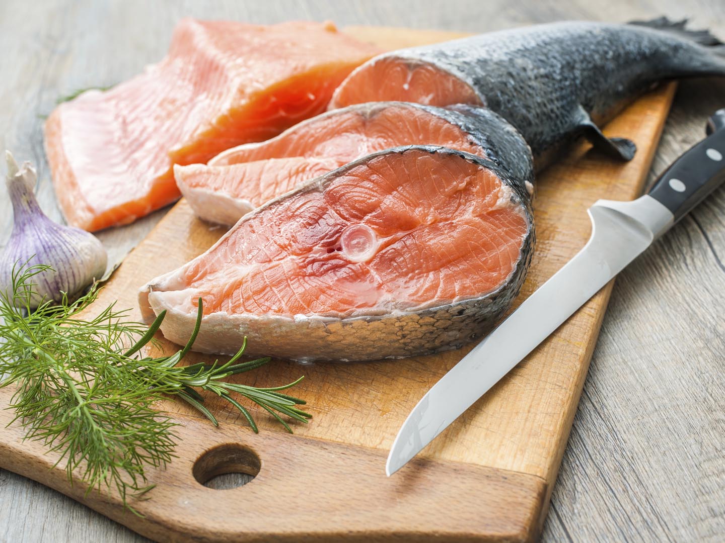 Raw salmon fish steaks with fresh herbs on cutting board, high cholesterol