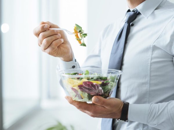 Businessman having a vegetables salad for lunch, healthy eating and lifestyle concept, unrecognizable person