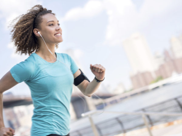 Determined female runner outdoors early in the morning listening to music with earphones