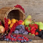 Harvested Summer Fruits and Berries an a wooden Table with its Basket.