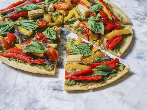 Super Healthy Vegan Gluten-free Pizza with Homemade Kale Basil Pesto, Roasted Vegetables on Chickpea Crust. Close up, selective focus.