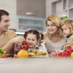 Happy family in the kitchen holding healthy food.