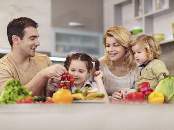 Happy family in the kitchen holding healthy food.