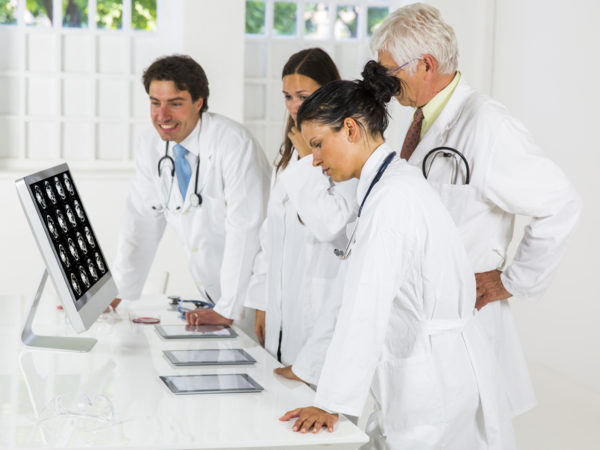 Young doctors  watching CAT scan picture of human abdomen on computer monitor