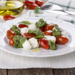 Caprese. Italian salad - mozzarella, tomato, basil, pesto.