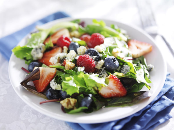 berry salad with walnuts and blue cheese on white table cloth shot close up