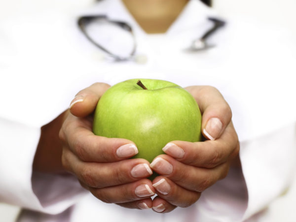 Doctor holds an apple in his hands. (High key image)