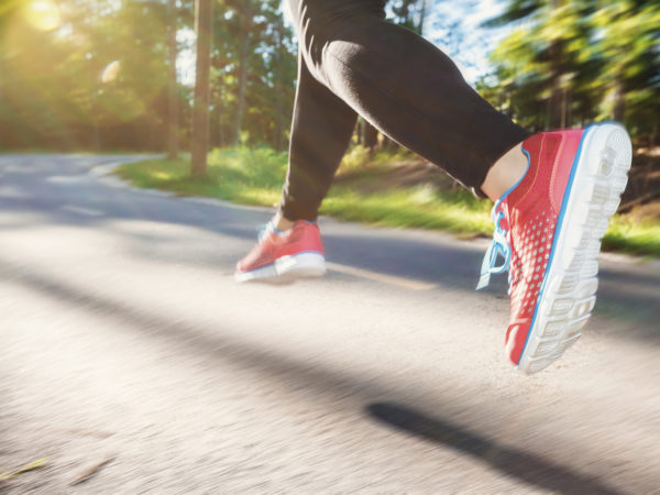 Woman jogging down an outdoor trail at sunset