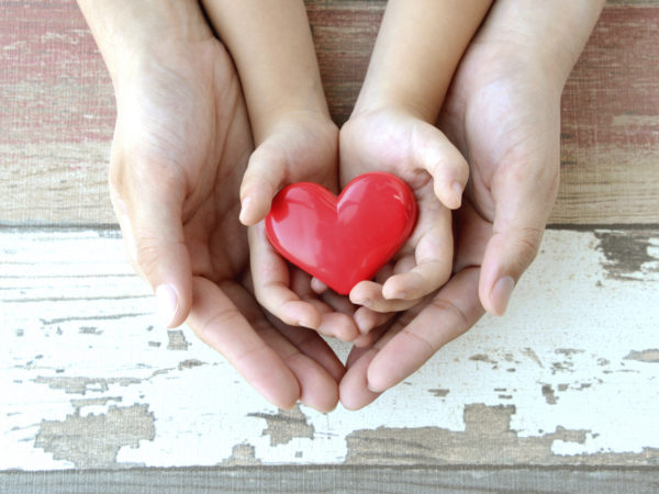 Red heart in child and mother&#039;s hands