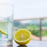 Glass of water with lemon isolated on white background