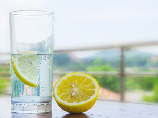 Glass of water with lemon isolated on white background