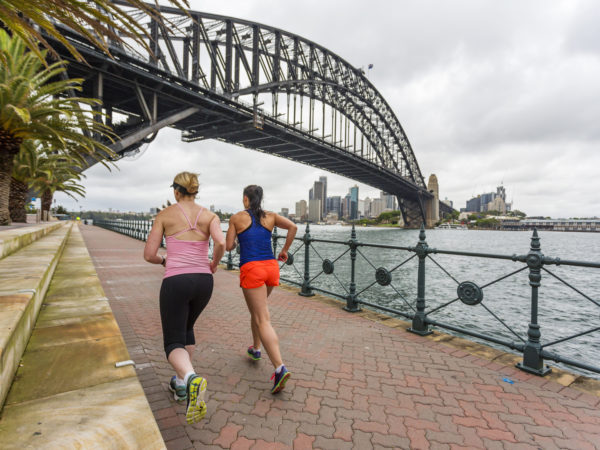 A woman and her personal trainer running under stormy skies by Sydney Harbour
