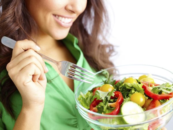 Close-up of pretty girl eating fresh vegetable salad