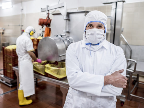 Man working at a food processing plant wearing full uniform