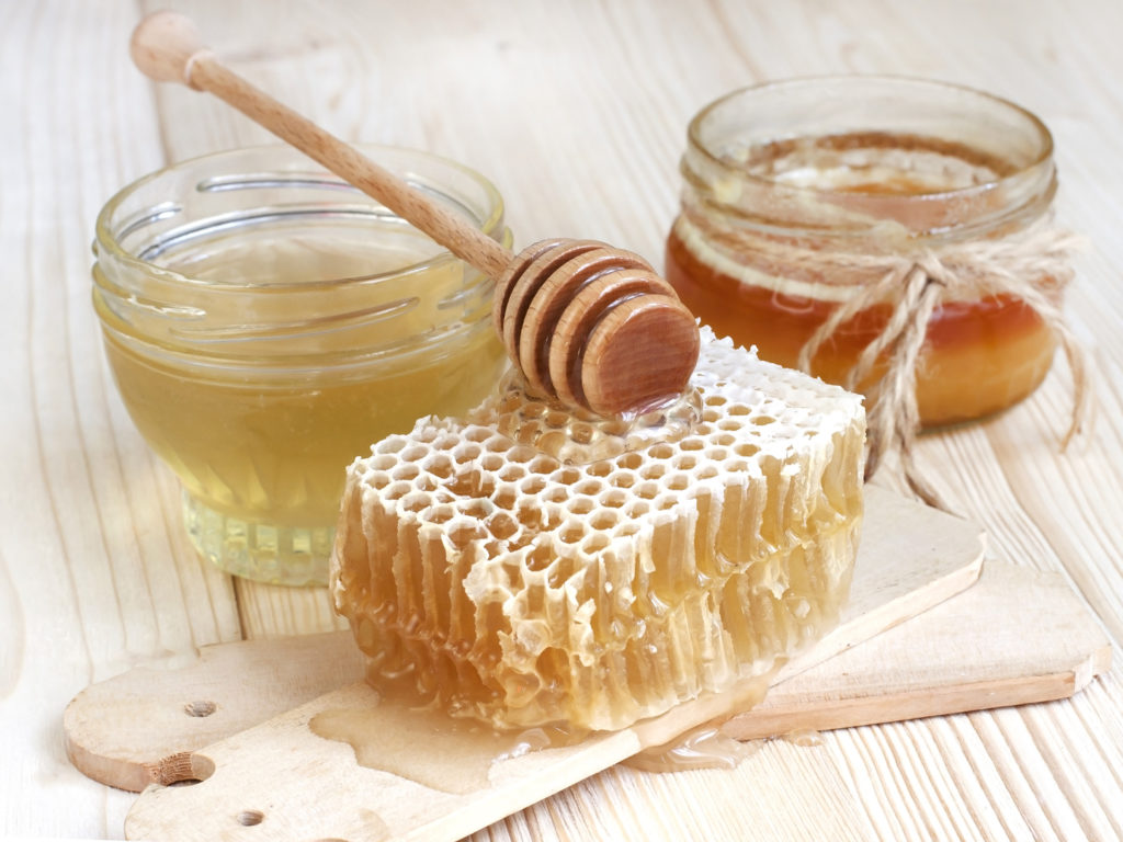 Glass cans full of honey on wooden table