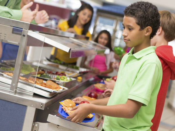Middle school students getting lunch items in cafeteria line.