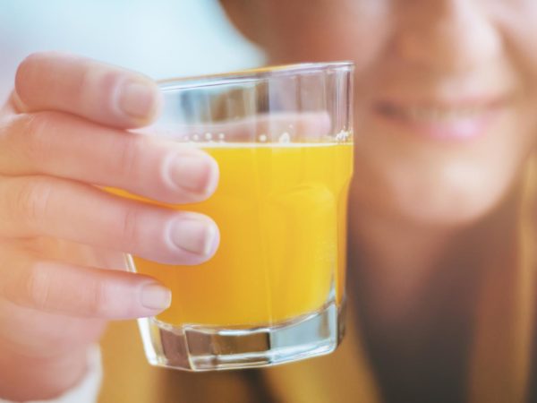 young woman holding glass of orange juice