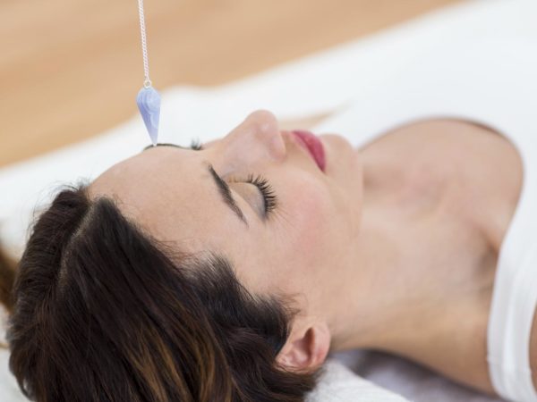 Woman being hypnotized while lying on the wooden floor