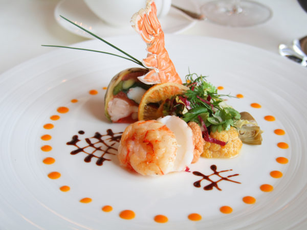Starter or Entree of a french dish with seafood mixed among salad leaves.