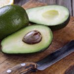 Sliced avocado and knife on old cutting board. Guacamole ingredients.