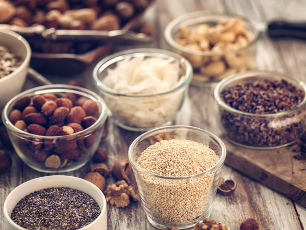 Superfoods in Bowls like chia, quinoa, cocoa, almonds and cashew on wooden background.