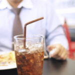 Fat and unhealthy businessman having soft drink and junk food (focus on soft drink, blurred out the rest) - unhealthy and junk food concept