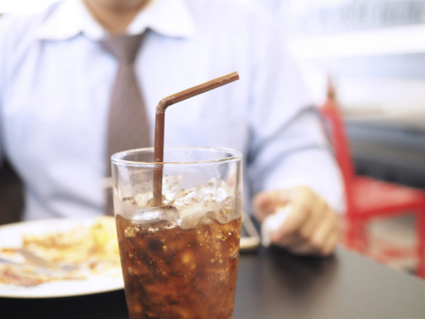 Fat and unhealthy businessman having soft drink and junk food (focus on soft drink, blurred out the rest) - unhealthy and junk food concept