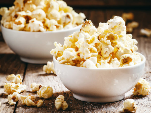 Sweet popcorn in white bowls, vintage wooden background, selective focus