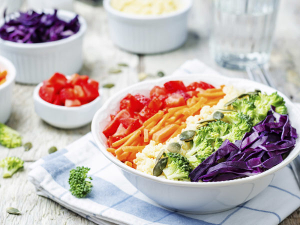 rainbow millet vegetable salad on white wood background. toning. selective focus