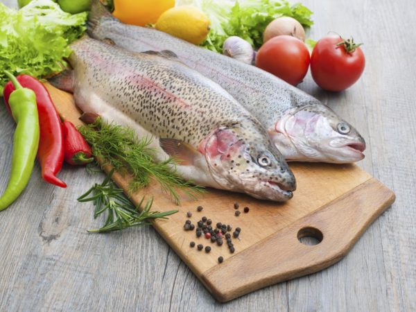 fresh trout, vegetables and spices on a cutting board