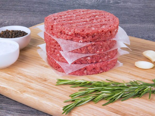 Fresh Burger patties on a wooden cutting board.