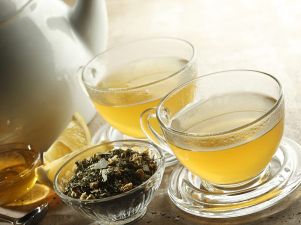 &quot;Two glasses of tea.  Teapot,honey, lemon, and loose tea beside cups.&quot;
