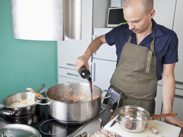 Mid adult caucasian man cooking with wine at home.