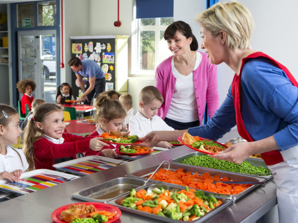 Dinner is served out to children as they line up at a school canteen