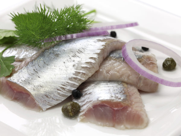 pickled herring, cold appetizer on white dish