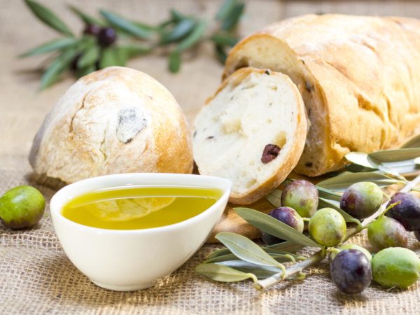 Ciabatta bread with olive oil and olive branch on burlap.